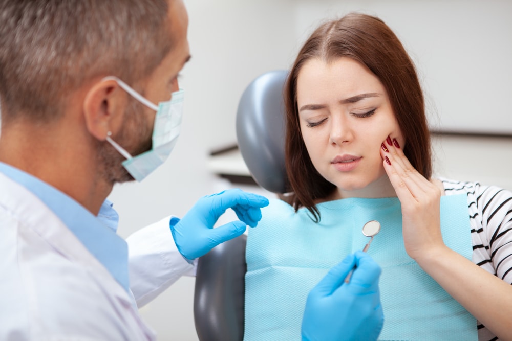 A woman is being examined by a dentist to understand symptoms of root canal need.
