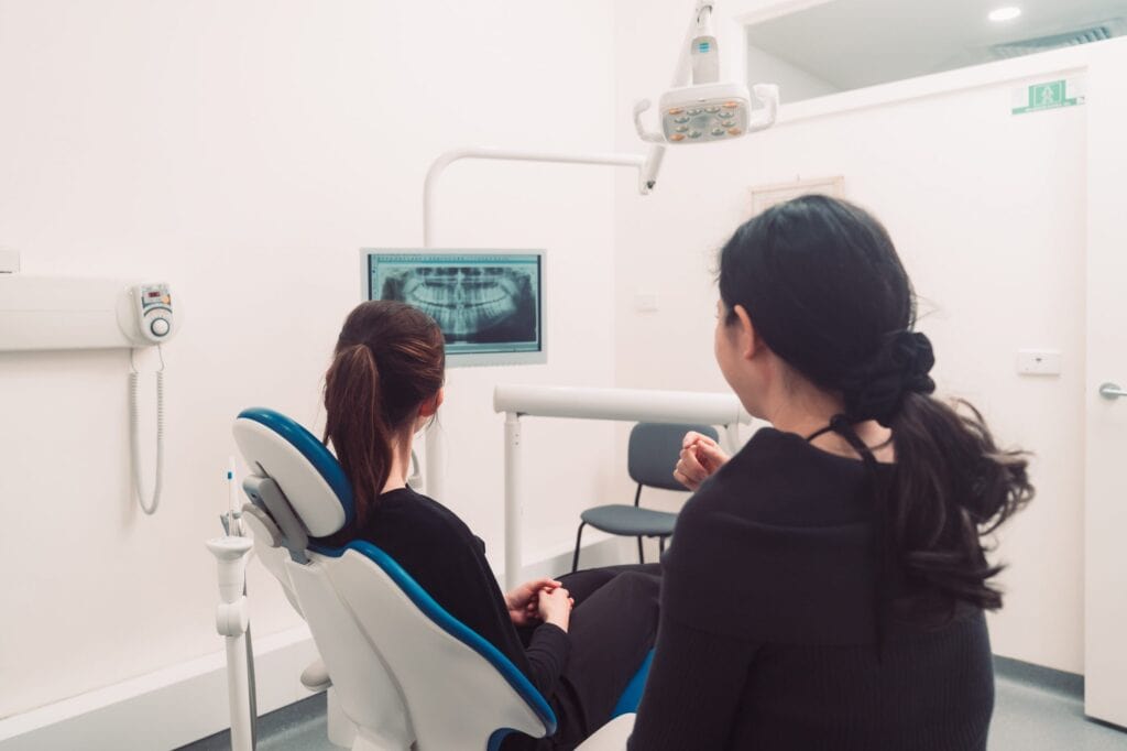 Two anxious women sitting in a dental chair.